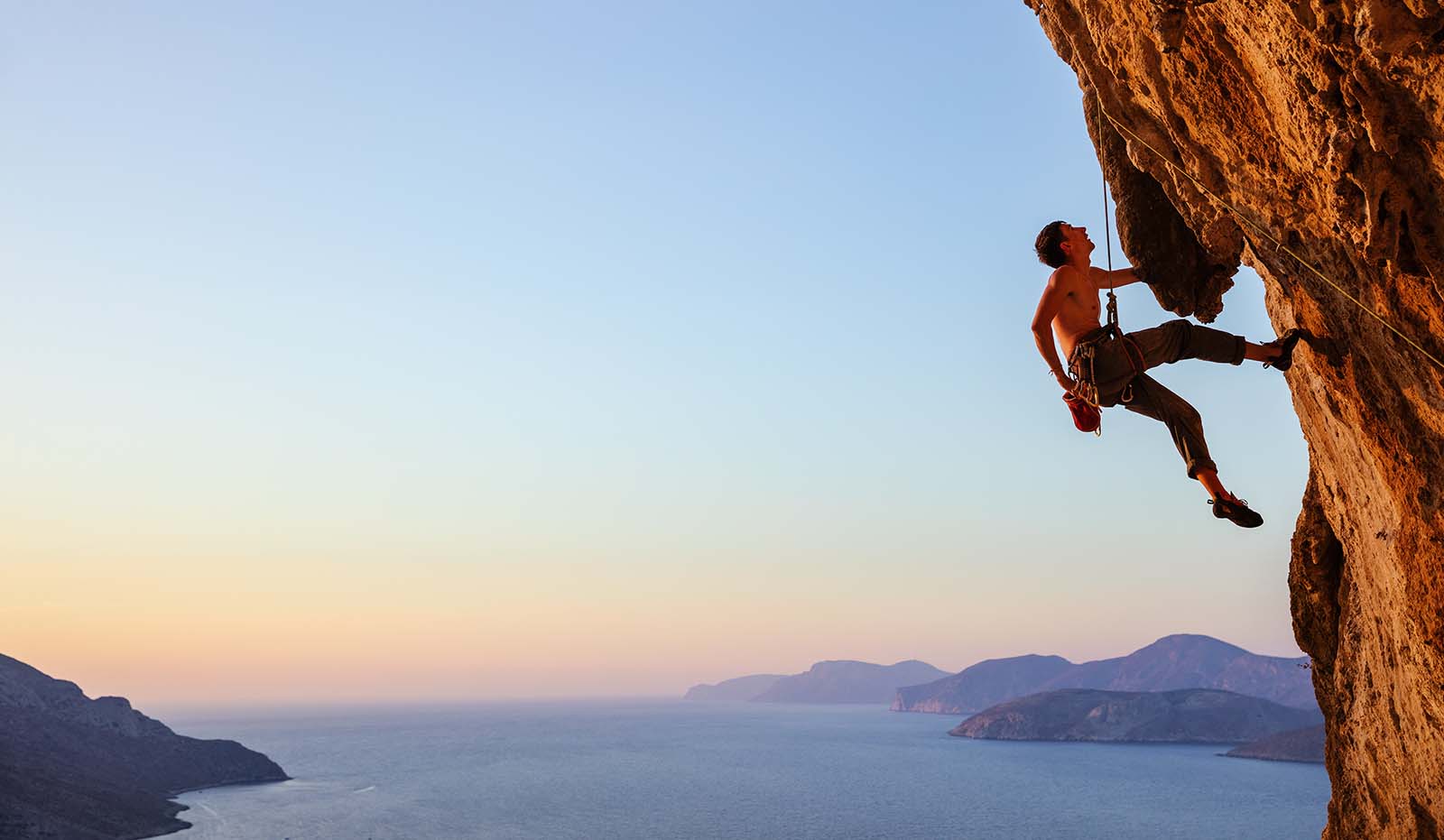 man scaling large boulder